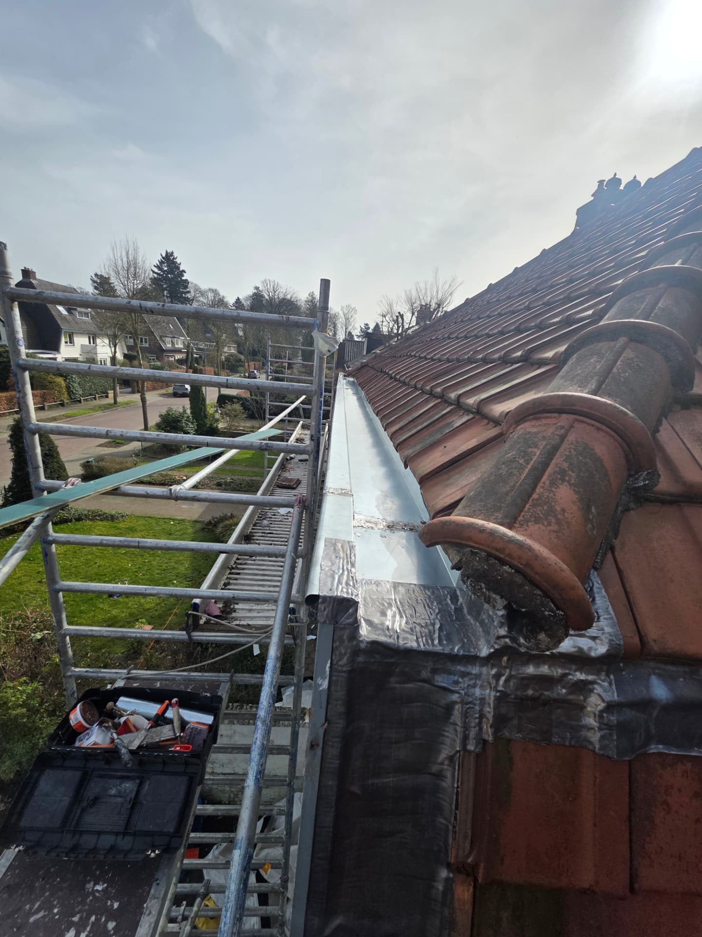 Nieuw geplaatste zinken dakgoot langs het pannendak