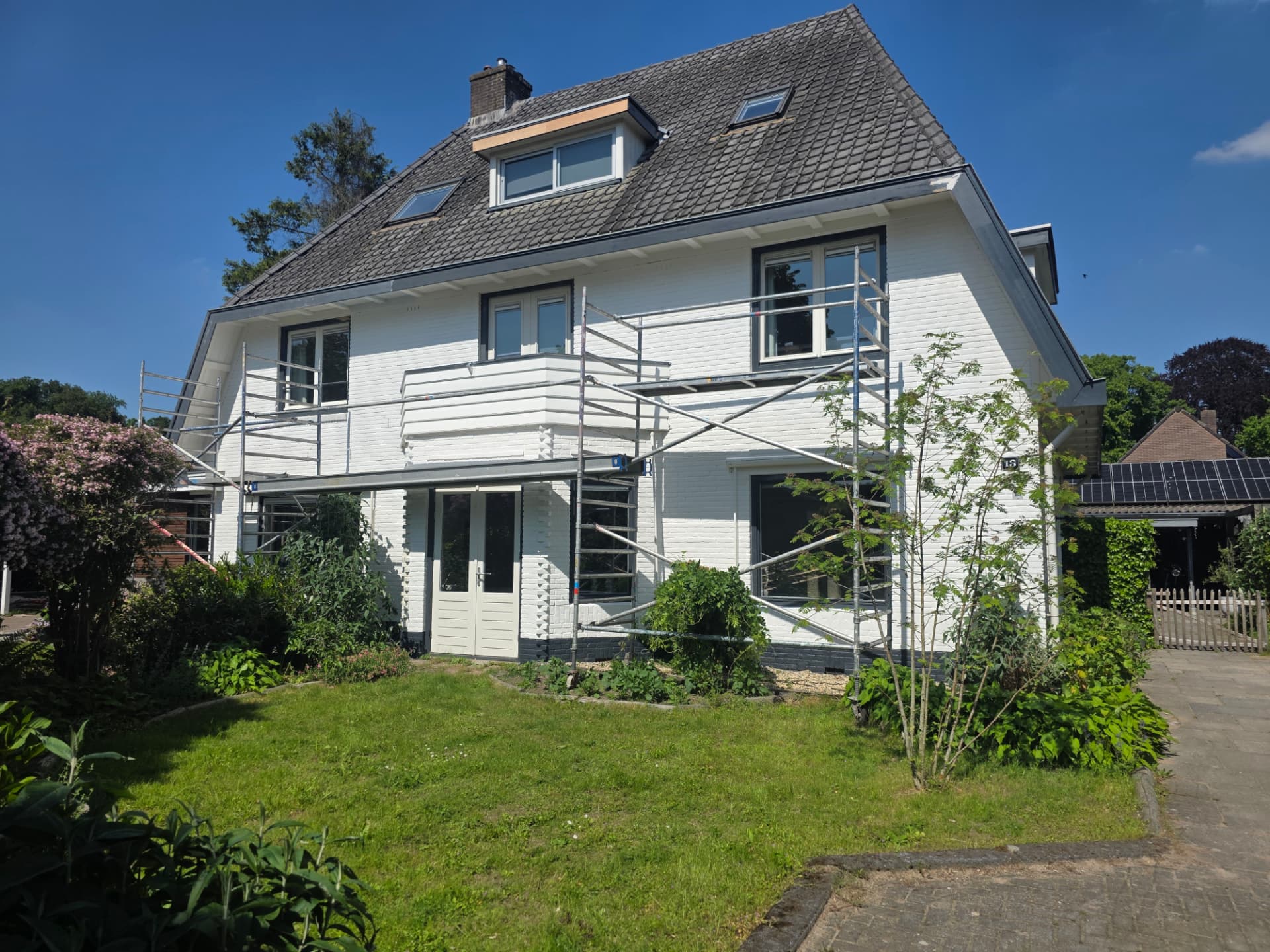 Authentiek wit woonhuis met steiger tijdens schilderwerk en onderhoud aan de dakgoten